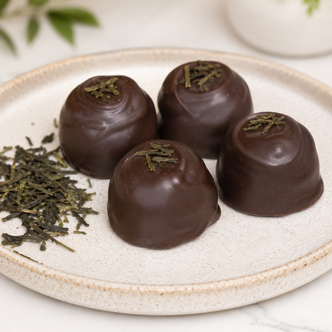 Chocolate truffles with tea leaves on a white plate